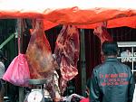 the market stalls with sinewy beef backs hanging 
in the open air