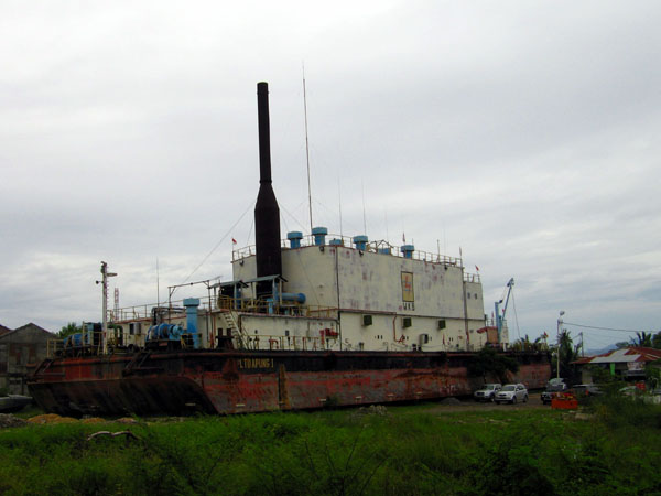 twenty minutes down a washed out road
Is a rusty container ship, lying across a weedy pitch,
Three miles from the coast