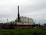 twenty minutes down a washed out road 
Is a rusty container ship, lying across a weedy pitch, 
Three miles from the coast