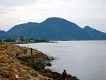 First it is a gentle hill on a plane. As it rises, 
it sucks at the corners of the sea, 
revealing bare sand inside the seawall,